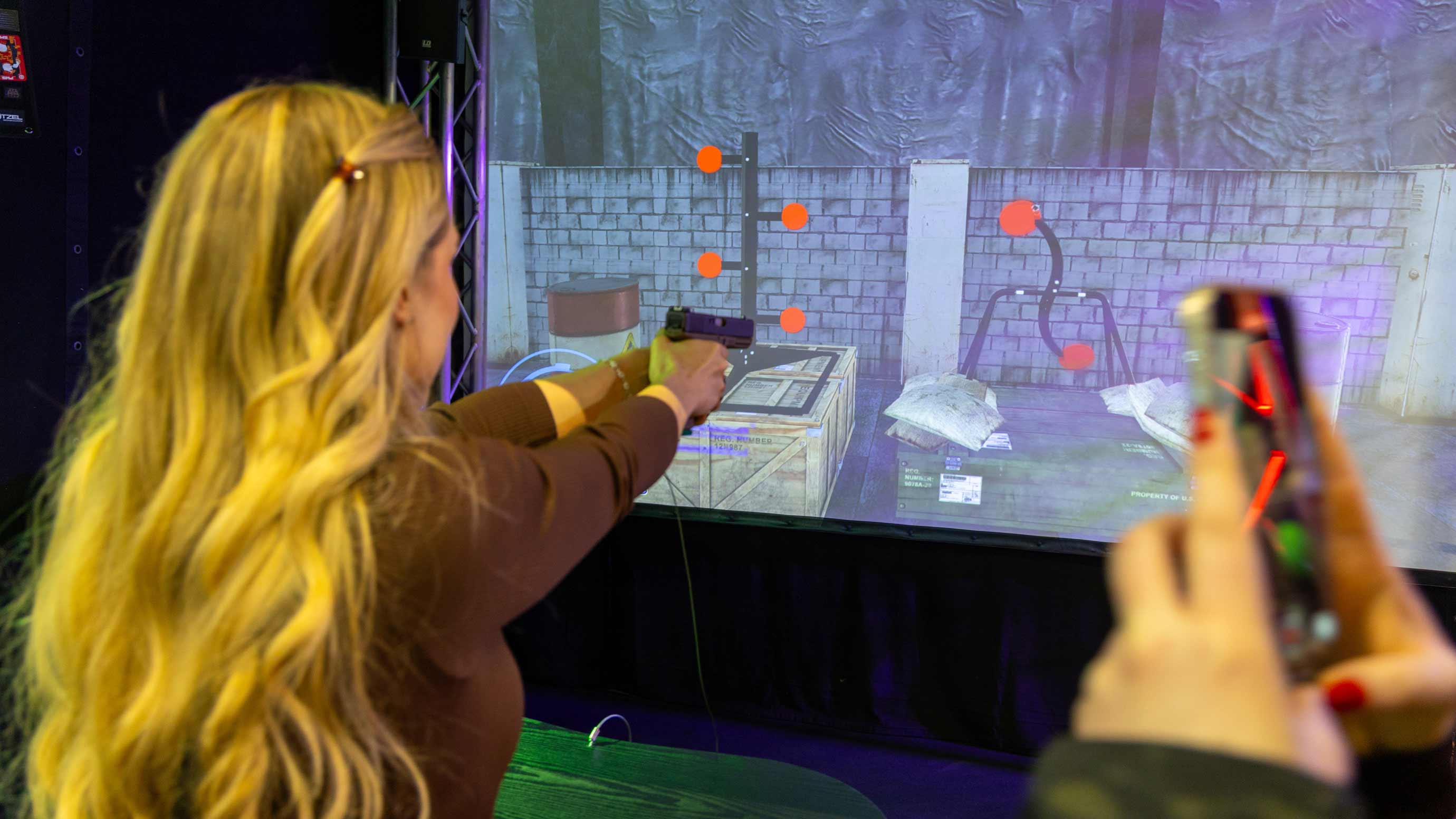 Person shoots at a screen with a virtual game on it